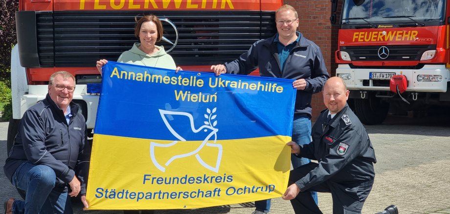 Sie sehen: Fachbereichsleiter Michael Alfert, Bürgermeisterin Christa Lenderich, Verwaltungsmitarbeiter Lars Wiggenhorn und Feuerwehrleiter Andreas Leusing (v.l.) vor dem Löschfahrzeug mit einem Banner der Ukrainehilfe.