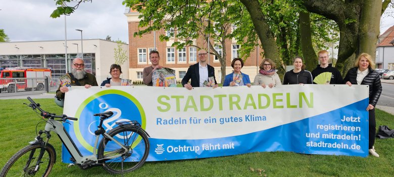 Sie sehen: ein Gruppenbild hinter dem Banner von STADTRADELN