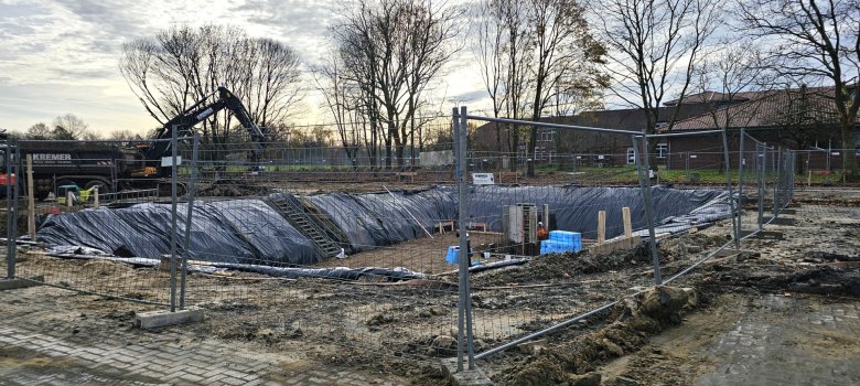 Sie sehen: den Kelleraushub an einer Baustelle mit Bauzaun.