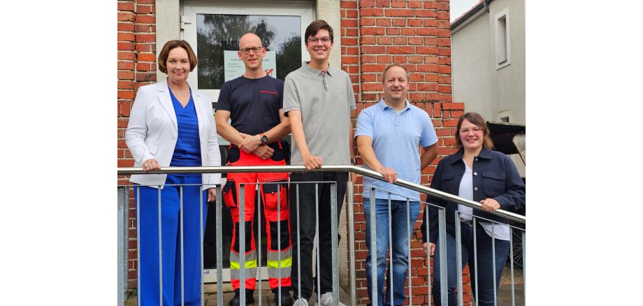 Sie sehen: eine Menschengruppe auf der Treppe vor dem Rathauseingang