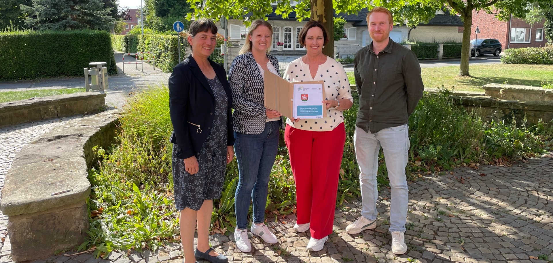 Sie sehen: eine Menschengruppe vor einer Grünanlage (v.l.: Fachbereichsleiterin Karin Korten, Lisa Kukuk vom Mobilitätsnetzwerk, Bürgermeisterin Christa Lenderich und Denis Ultee von der Abteilung Planen, Umwelt und Klima).