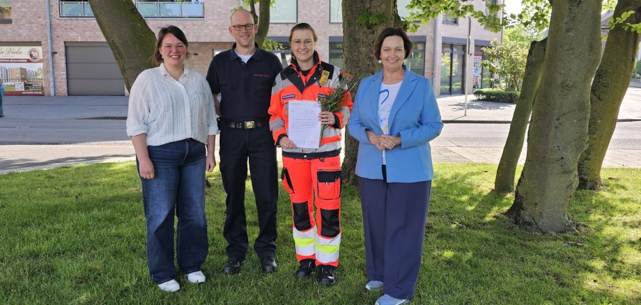 Sie sehen: eine Menschengruppe im Freien (v.l.: Ausbildungsleiterin Teresa Stauvermann, Wachleiter Roman Beunink, Viktoria Achtermann und Bürgermeisterin Christa Lenderich.)