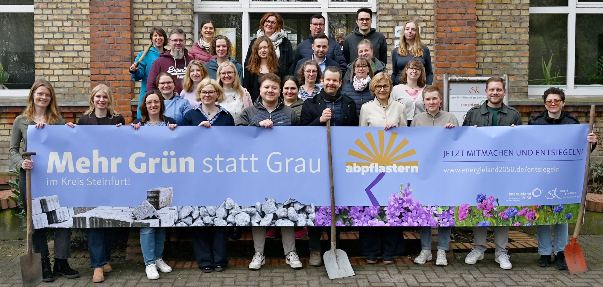 Sie sehen: Eine Gruppe Personen mit einem großen Banner zur Aktion "abpflastern"