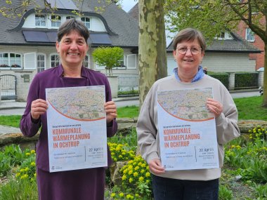 Sie sehen: zwei Personen, die ein Poster vor sich halten (FB III-Leiterin Karin Korten und Klimaschutzmanagerin Ursula Uphoff)