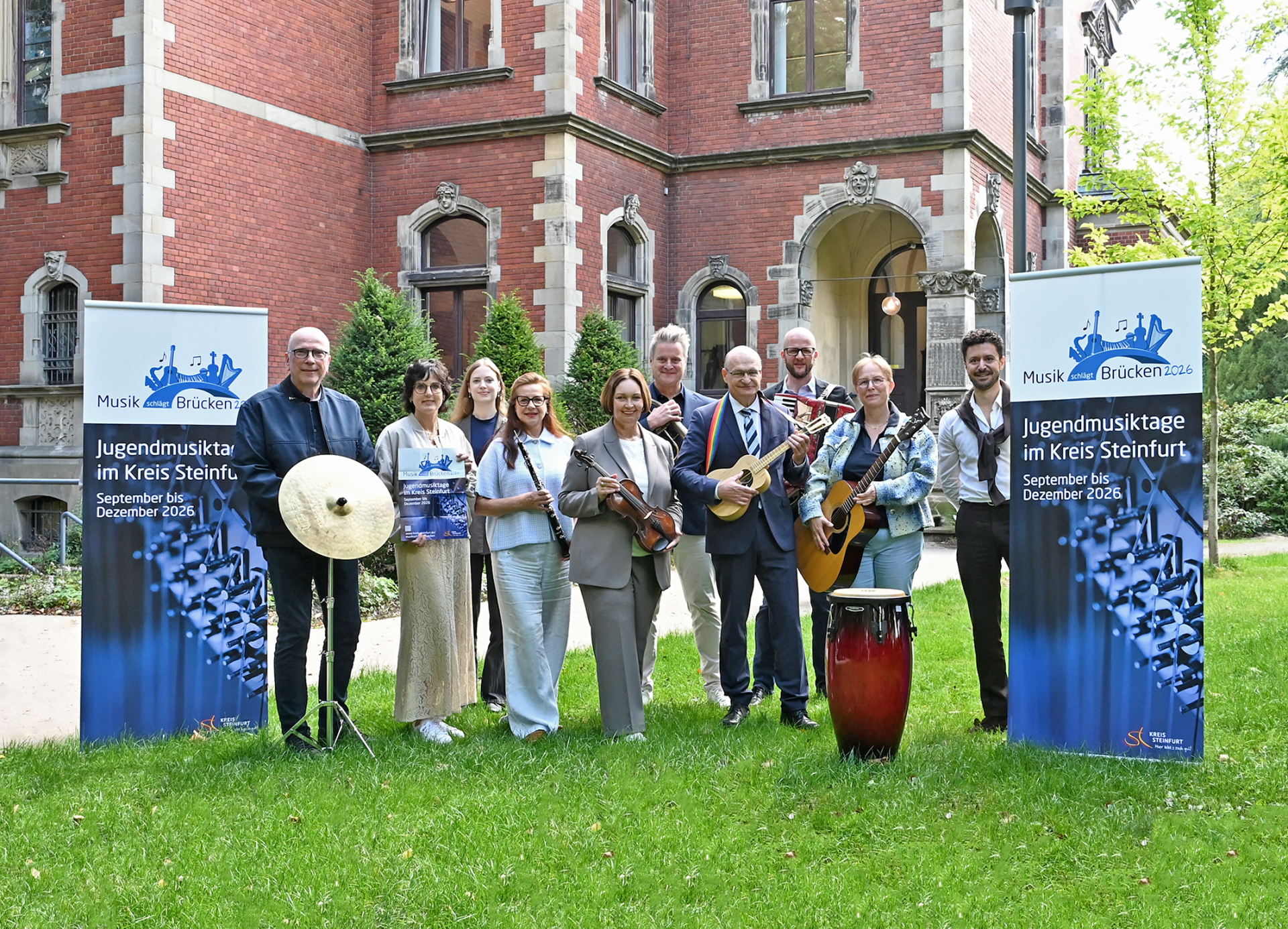 Sie sehen: Eine Gruppe von Menschen mit Musikinstrumenten und Bannern zum Projekt "Musik schlägt Brücken".