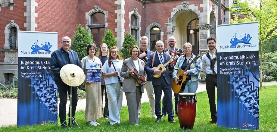 Sie sehen: Eine Gruppe von Menschen mit Musikinstrumenten und Bannern zum Projekt "Musik schlägt Brücken".