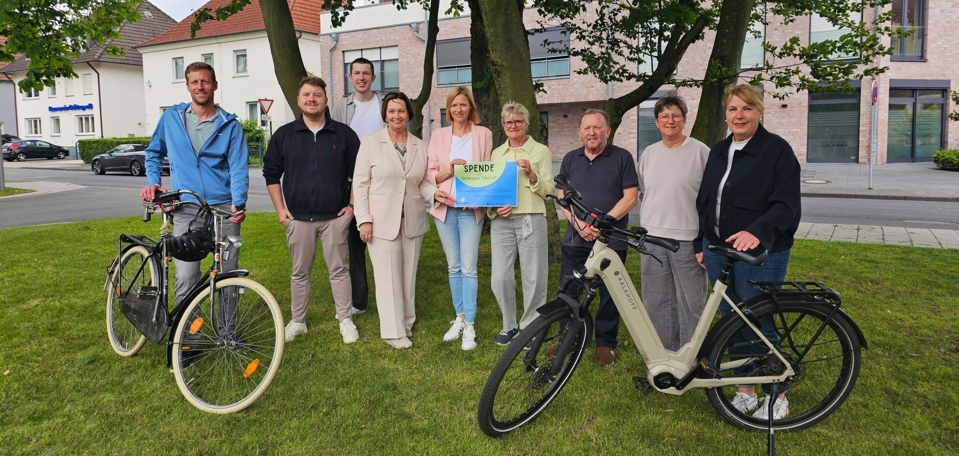 Sie sehen: eine Personengruppe mit Spendenurkunde und Fahrräder im Vordergrund.