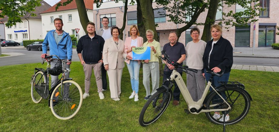 Sie sehen: eine Personengruppe mit Spendenurkunde und Fahrräder im Vordergrund.