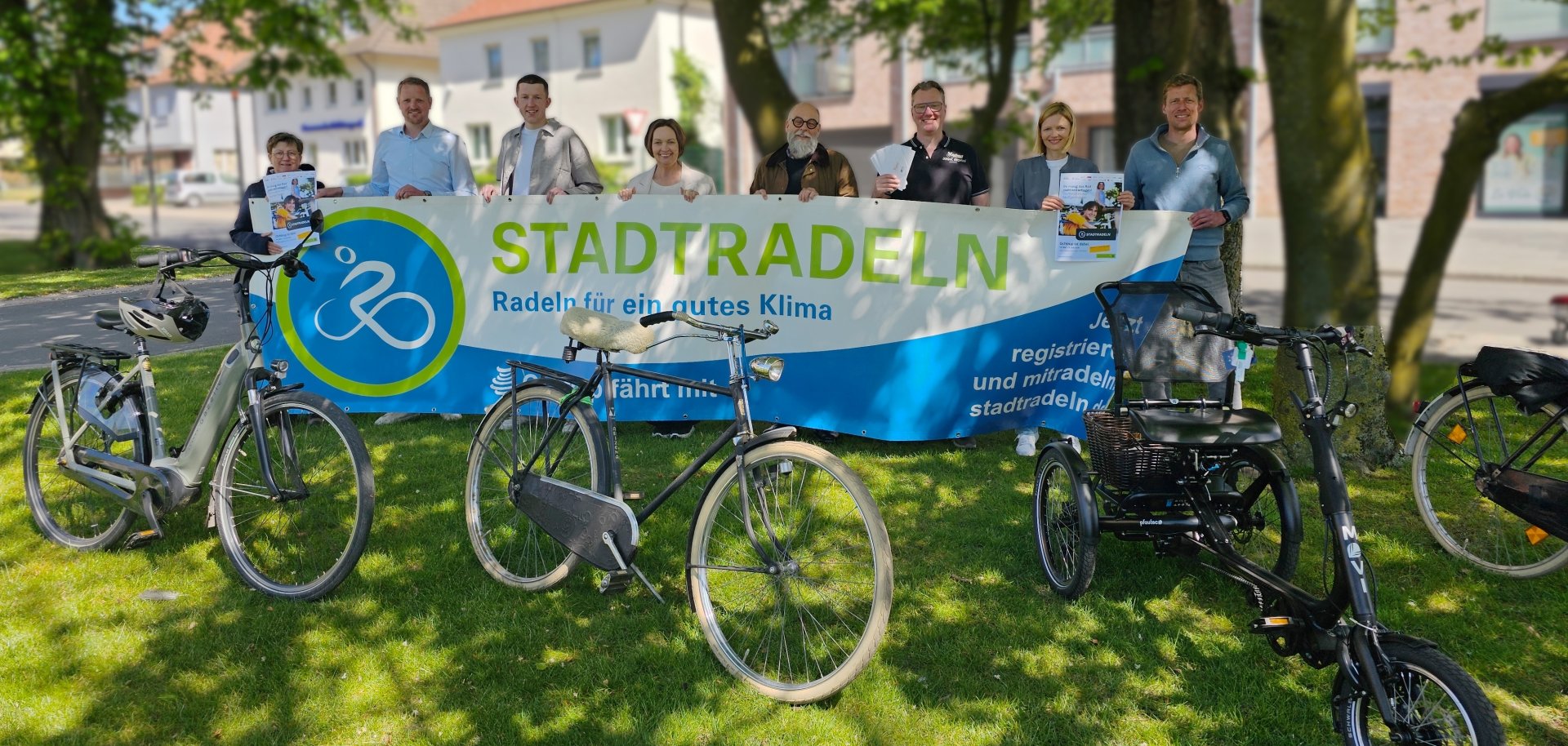 Sie sehen: Eine Gruppe von Personen hinter einem breiten STADTRADELN-Banner und Fahrräder im Vordergrund