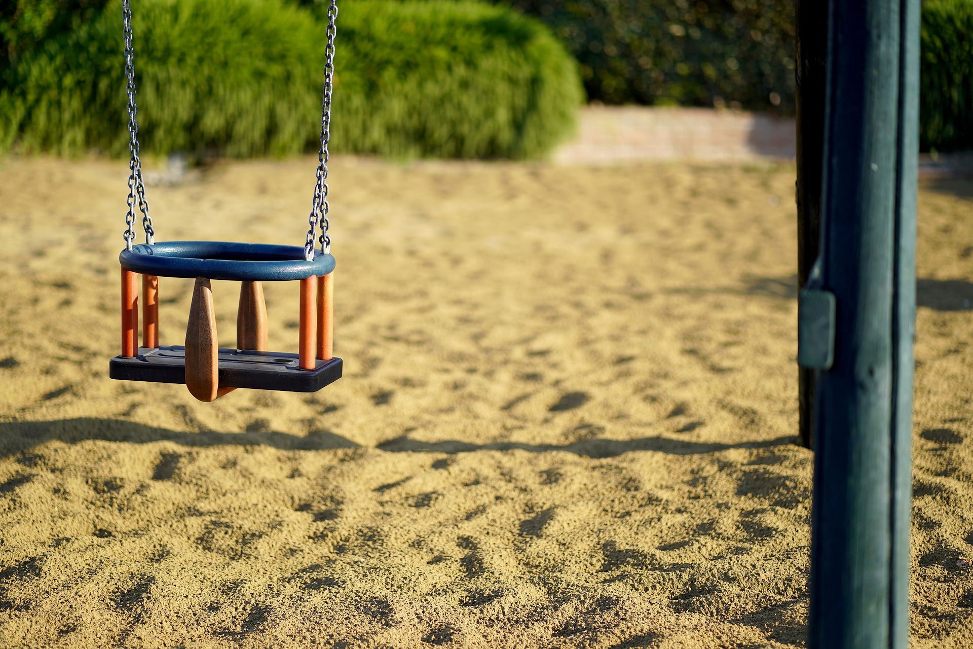 Kleinkindschaukel vor einem Sandplatz