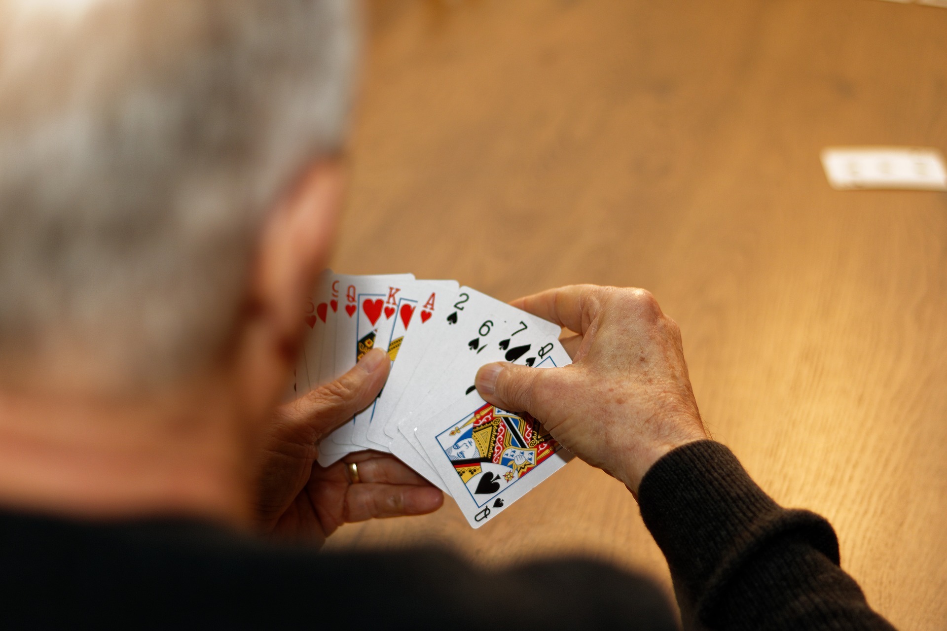 Mann blickt in die Spielkarten in seiner Hand