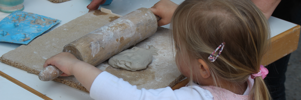 Kind rollt Ton mit einer Holzrolle aus