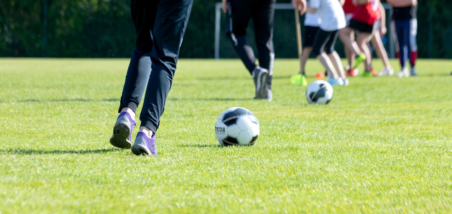 Fußball mit dribbelnden Beinen auf einem Bolzplatz