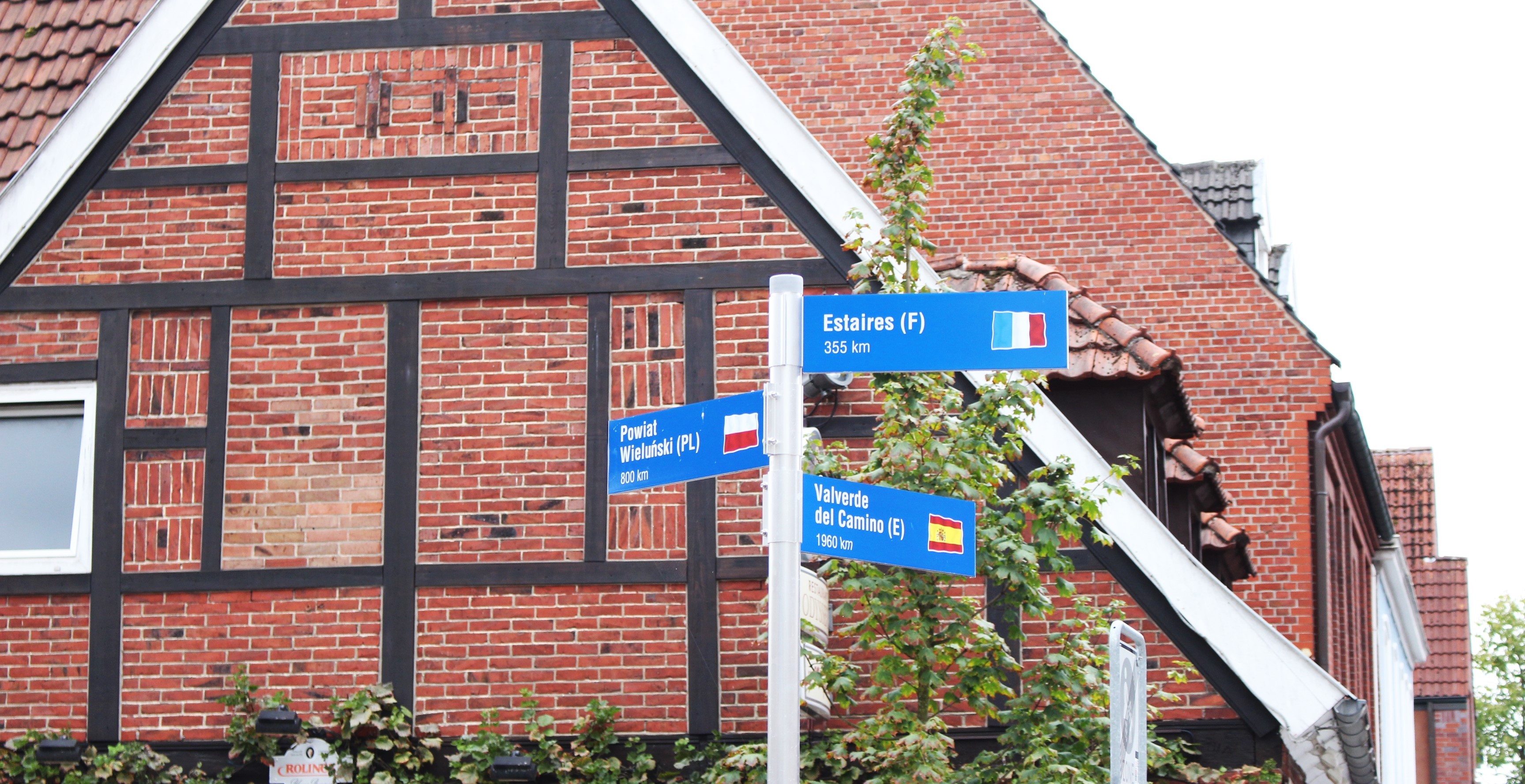 Wegweiser mit Aufschrift der Partnerstädte und Kilometerzahl