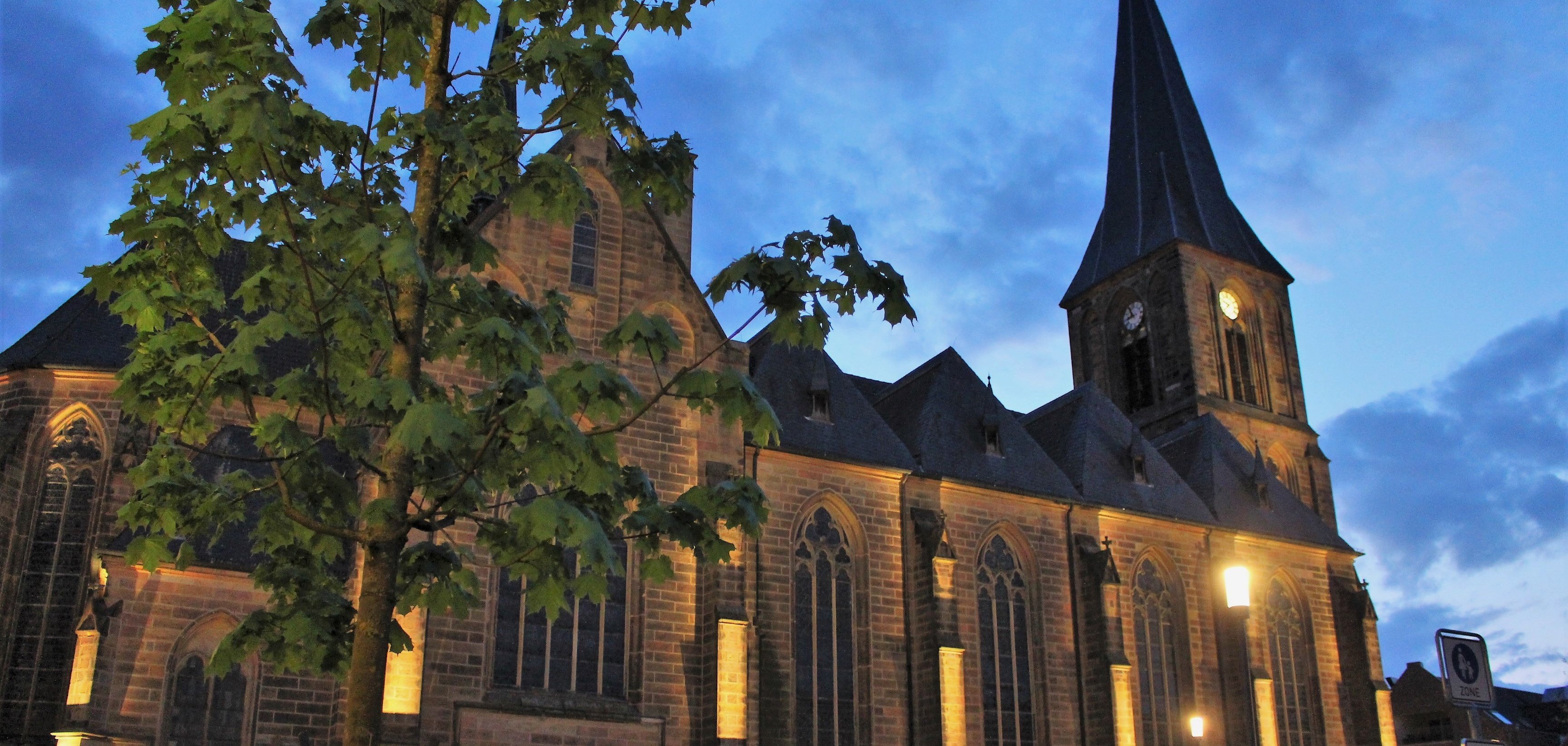 Sie sehen: die erleuchtete Lambertikirche bei Dunkelheit