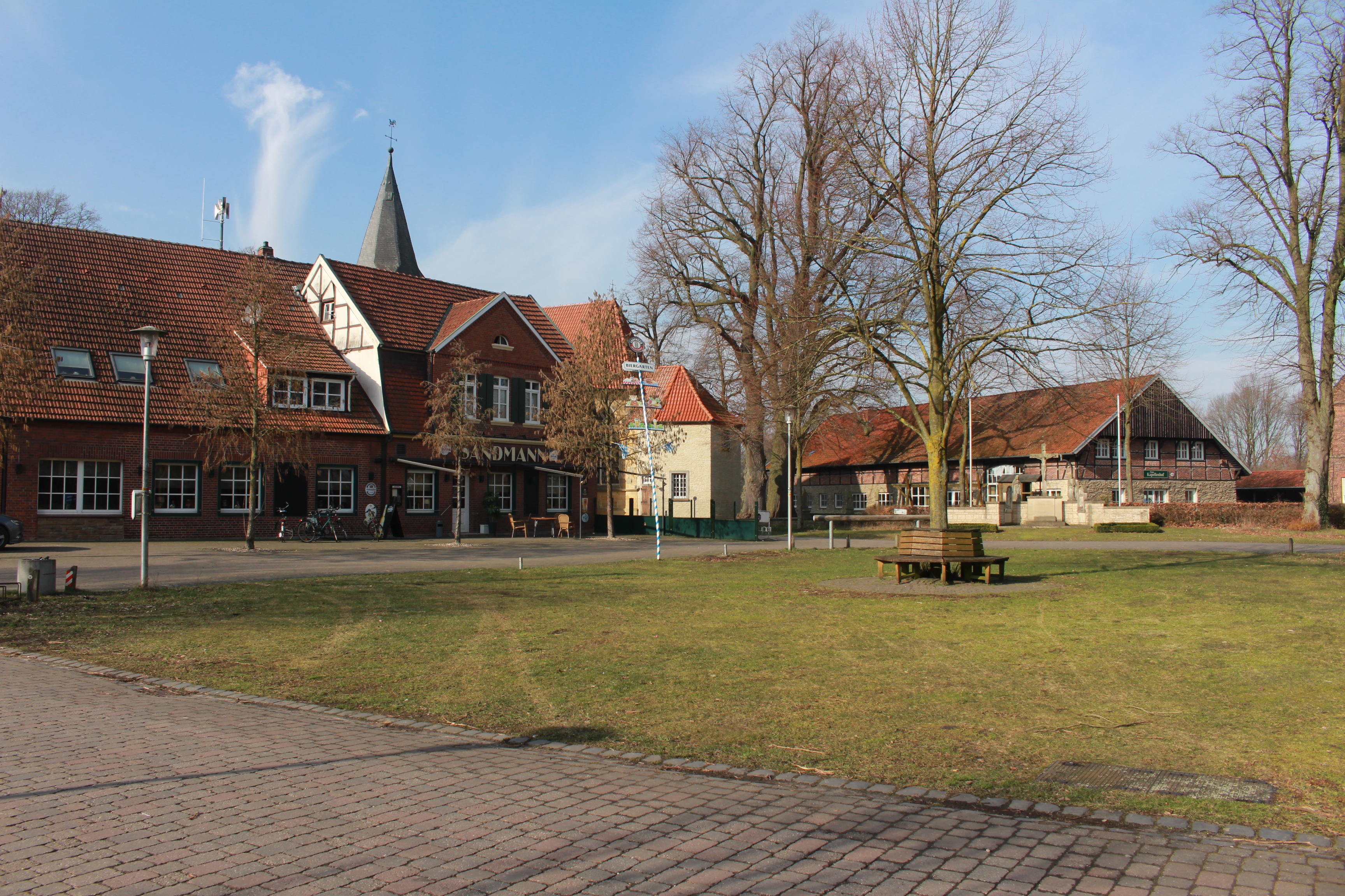 Sie sehen: eine Grünfläche mit Gasthof im Hintergrund (Dorfkern Welbergen)