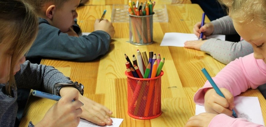 Kinder beim Malen an einem langen Tisch