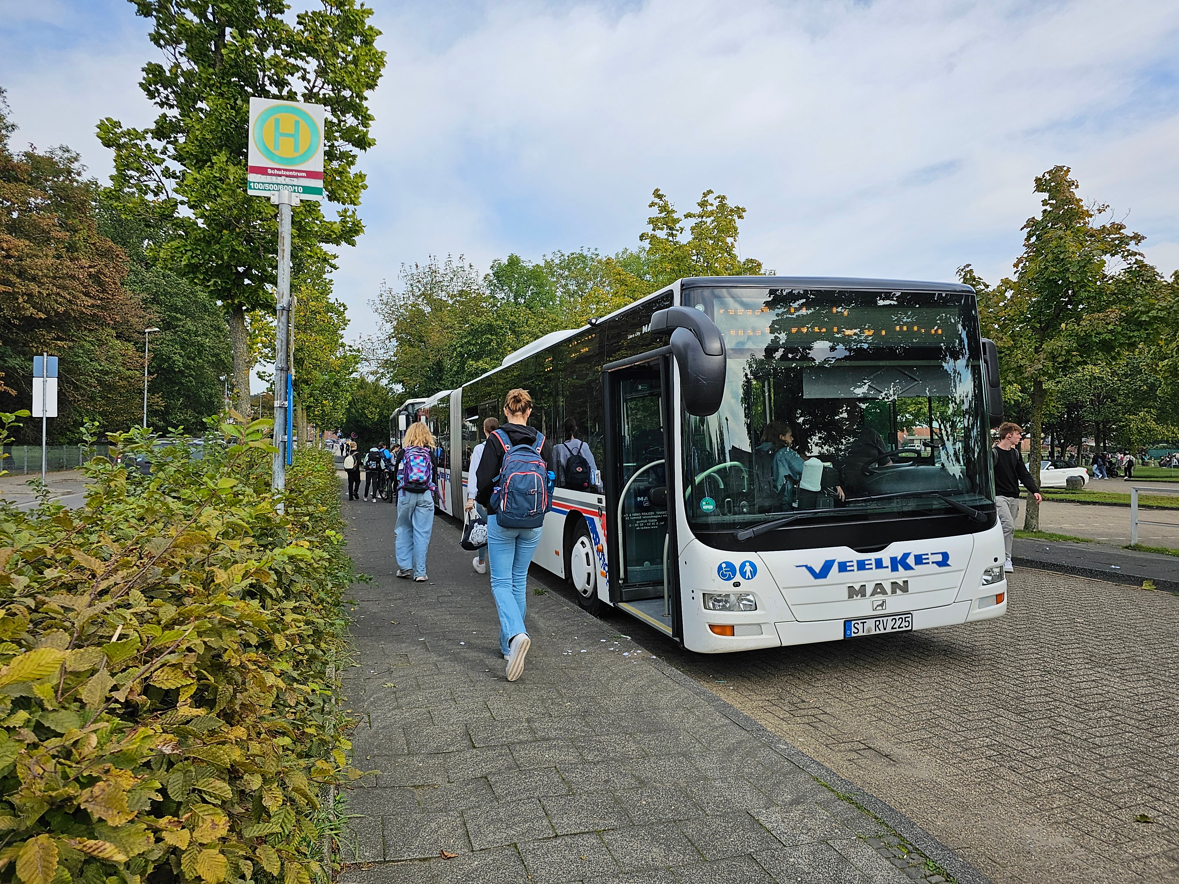 Sie sehen: einen parkenden Schulbus mit einsteigenden Schülern