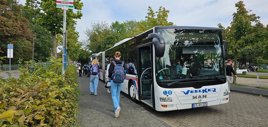Sie sehen: einen parkenden Schulbus mit einsteigenden Schülern