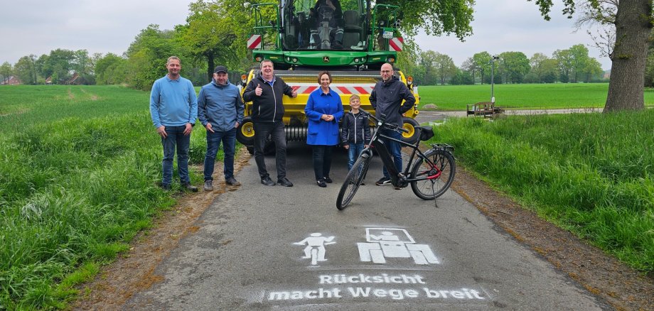 Sie sehen: eine Personengruppe vor einer Landmaschine