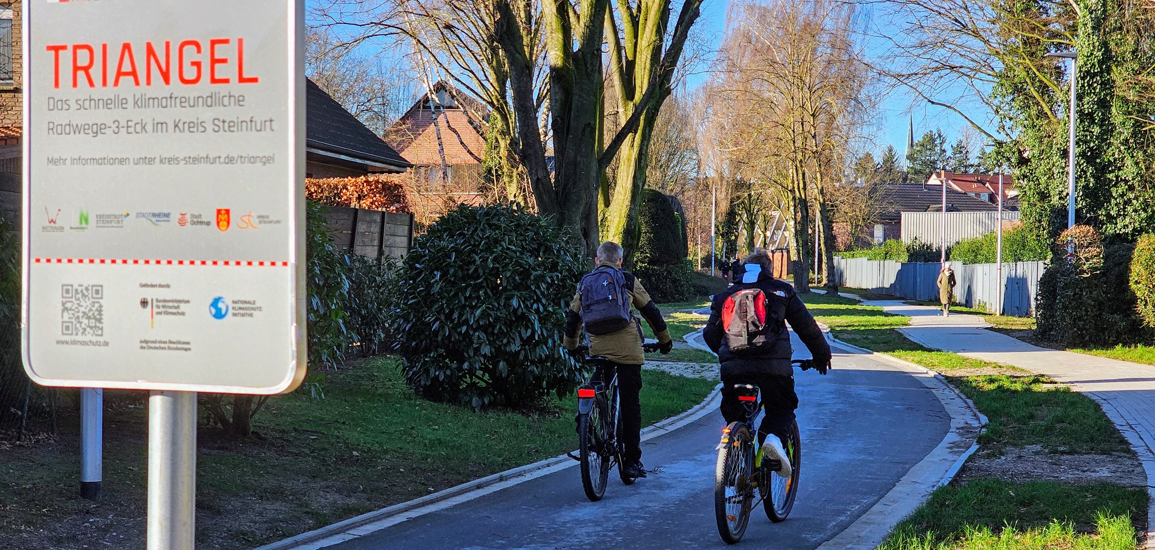Sie sehen: zwei Radfahrer von hinten auf einer Fahrradstarße