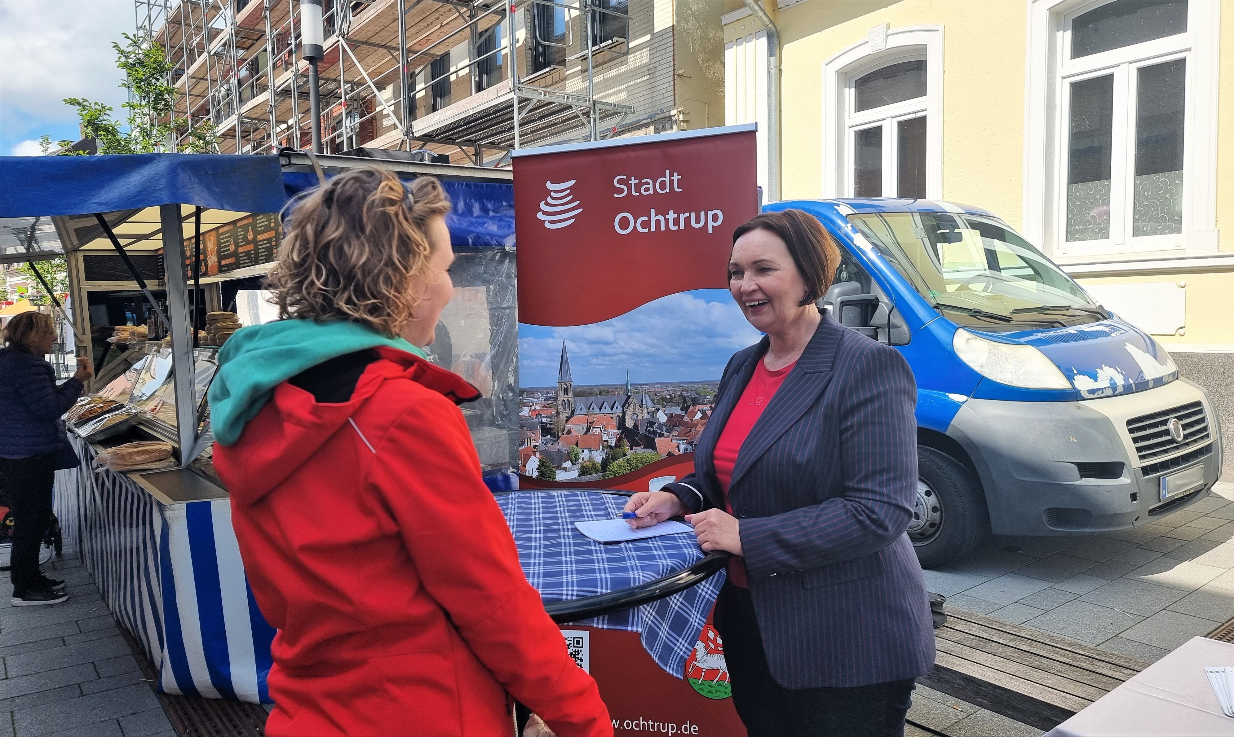 Sie sehen: Zwei Personen im Gespräch an einem Stehtisch: Bürgermeisterin Christa Lenderich auf der Wochenmarktsprechstunde
