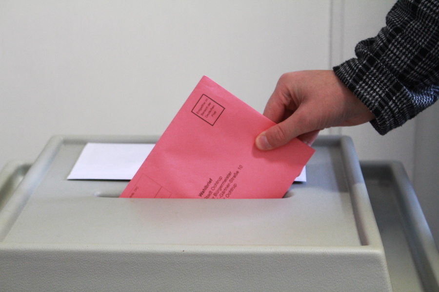 Briefumschlag wird in die Wahlurne geschoben