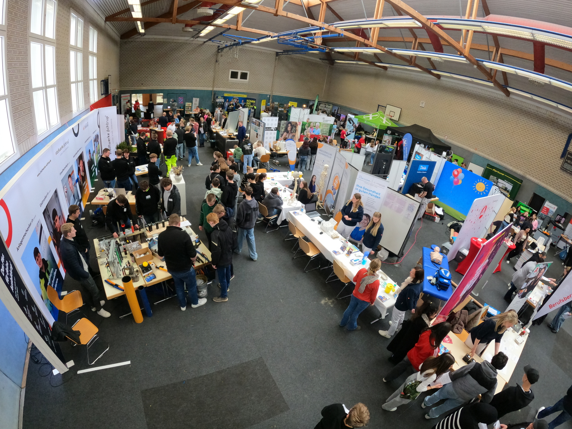 Sie sehen: Eine Luftansicht mit Messeständen in einer Halle
