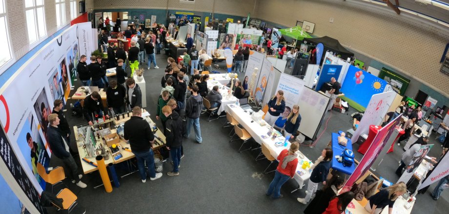 Sie sehen: Eine Luftansicht mit Messeständen in einer Halle