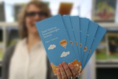 Frau hält Veranstaltungsbroschüren gefächert vor sich